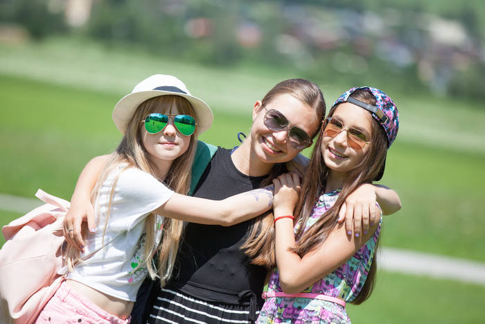 Gruppenfoto von 3 glücklich aussehenden Mädchen auf deren Gesichter die Sonne scheint während eines Lerncamps 