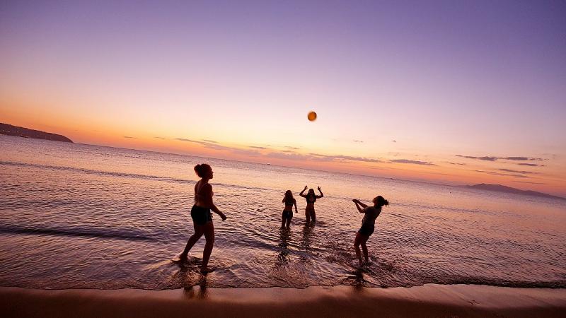 Freunde, die am Strand in der Dämmerung Ball spielen auf Schülersprachreisen Italien.