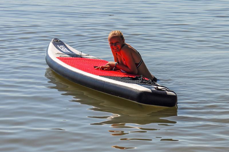 Bei der Sprachreise Spanien liegt ein Mädchen auf einem Surfbrett