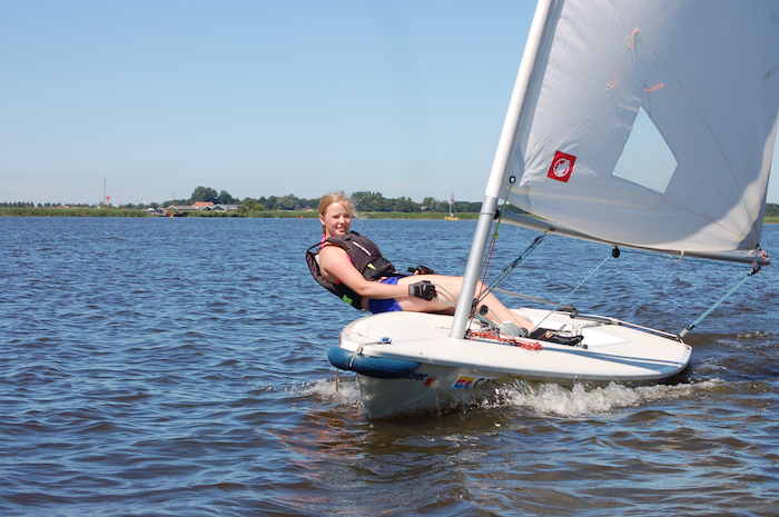 Ein Mädchen des Actioncamps sitzt auf einem Segelboot und segelt