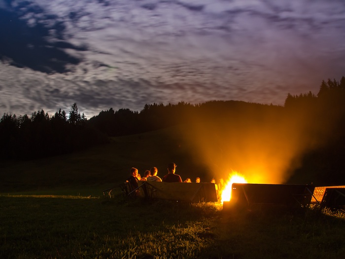 Die Teilnehmer der Feriencamps Österreich sitzen an einem Lagerfeuer