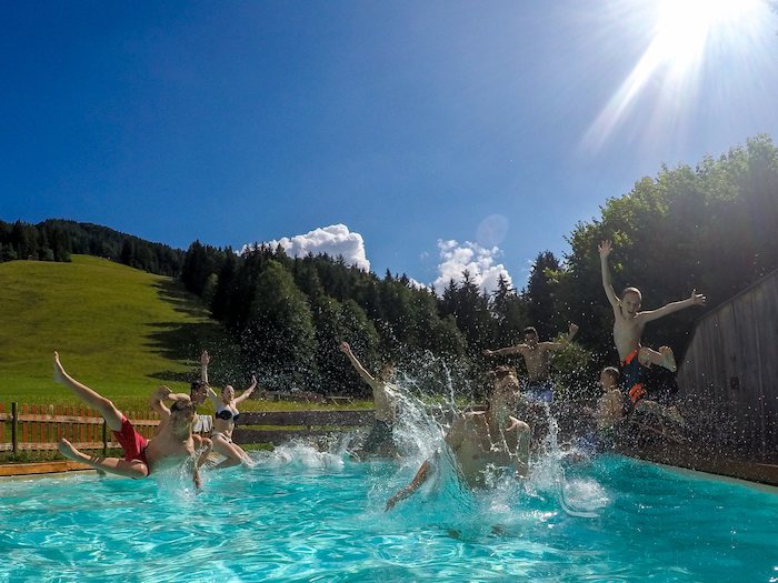 Eine Gruppe von Kindern springt in den Pool im Sportlager.