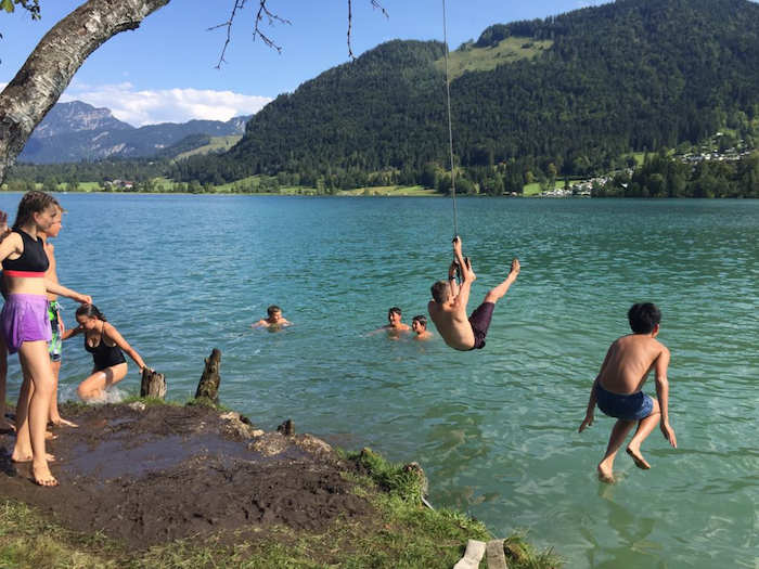 Im Ferienlager Freiburg schwingen die Kinder an einem Seil ins Wasser