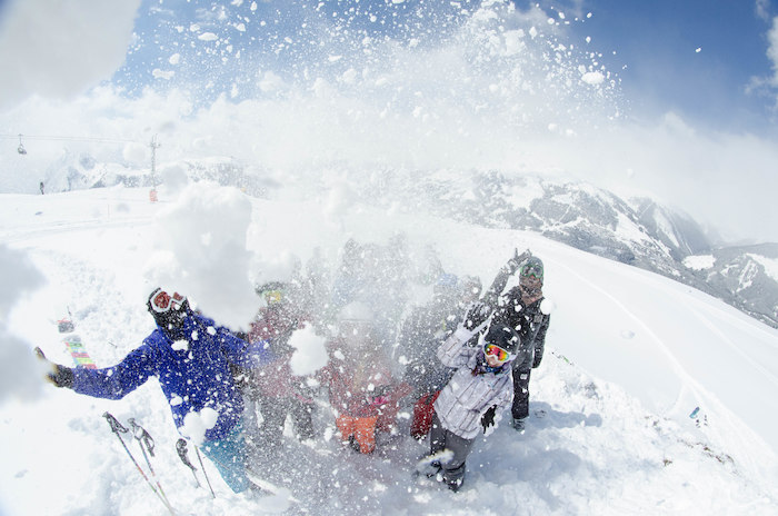 Eine Gruppe macht ein Selfie und wirft dabei eine Menge Schnee in die Luft.