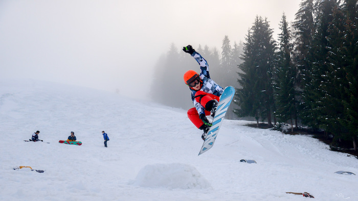 Eine Person fliegt mit dem Snowboard durch die Luft nach einem Sprung im Skilager.