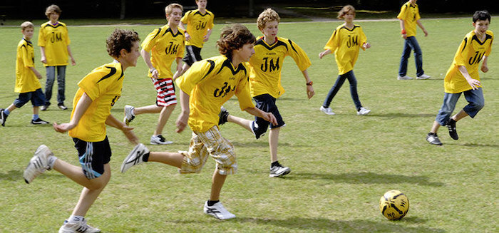 Eine Gruppe spielt in gelben Trikots Fussball während der Sprachferien in England