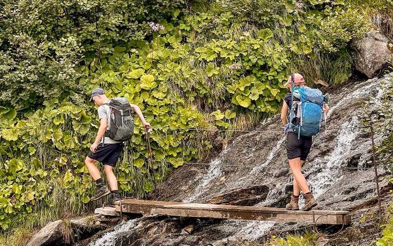 Zwei Campteilnehmer klettern über Wasserfall