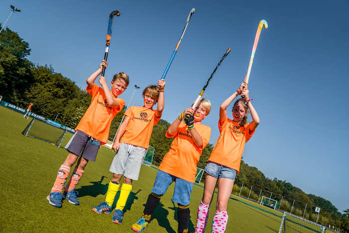 Teilnehmer eines Sport-Camps Kinder heben ihre Hookey Schläger über ihren Köpfen in die Höhe