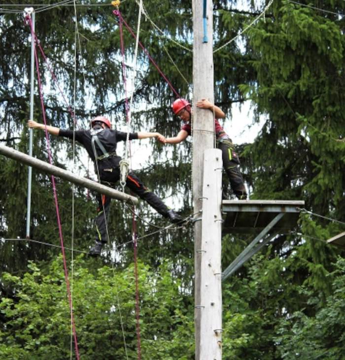 Zwei Personen helfen sich beim klettern im Ferienlager Kinder Schweiz