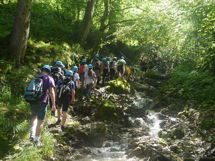 Im Ferienlager Graubünden wandert eine Gruppe Kinder und Jugendliche in der Natur
