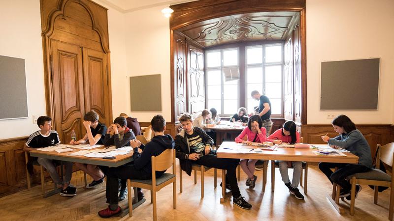 Ein paar kleine Grüppchen sitzen gemeinsam beim Sprachunterricht