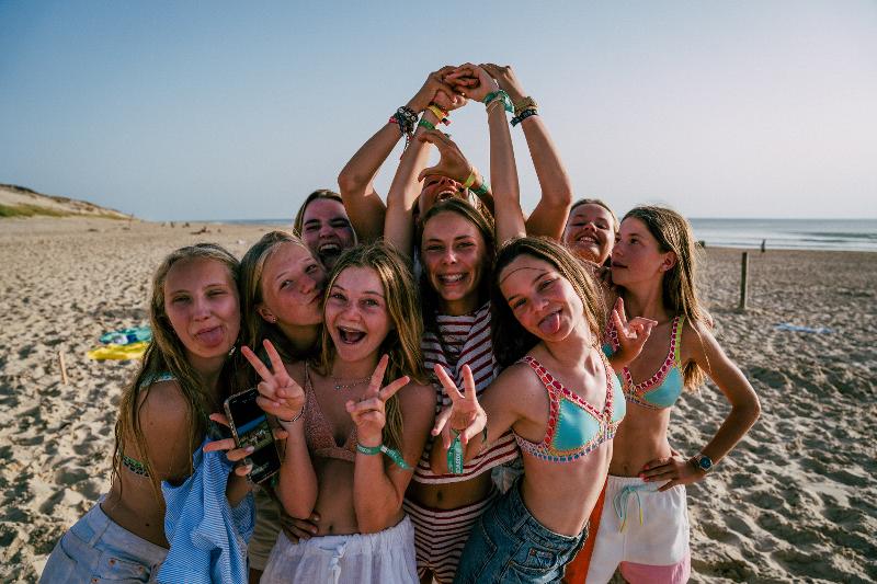 Eine Gruppe von Jugendlichen macht ein gemeinsames Foto am Strand vor dem Surfen, für die Erinnerung