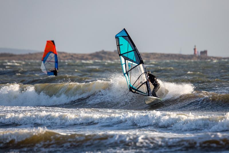Im Jugendurlaub sind Teilnehmer beim Windsurfen auf grossen Wellen zu sehen