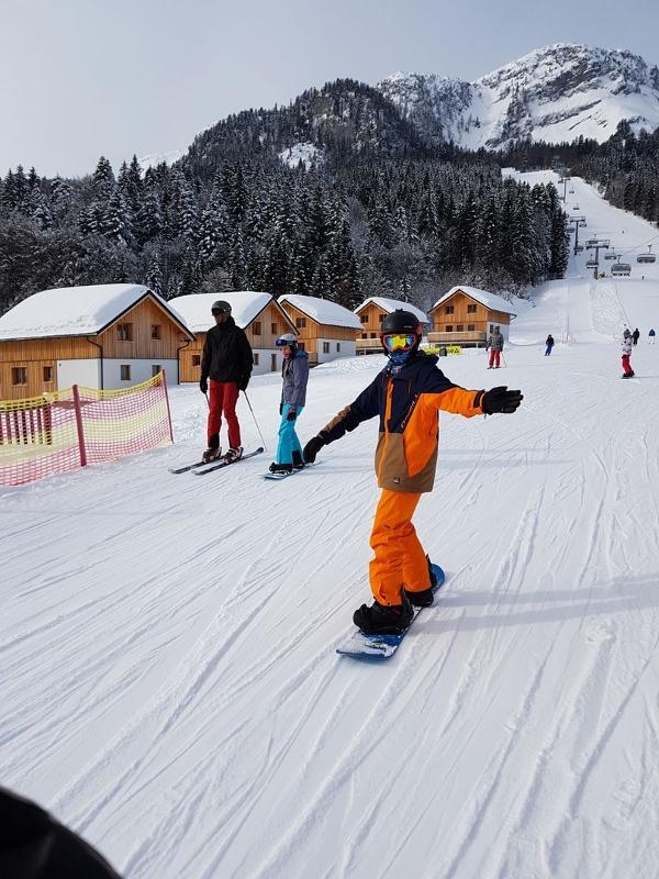 Teilnehmer eines Ferienlager Winter fährt mit Snowboard den Abhang hinab