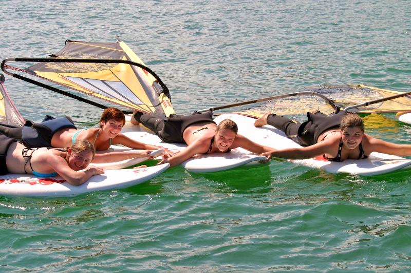 Drei Mädchen liegen auf ihren Surfbrettern und machen eine Pause in der Sommerfreizeit Kinder