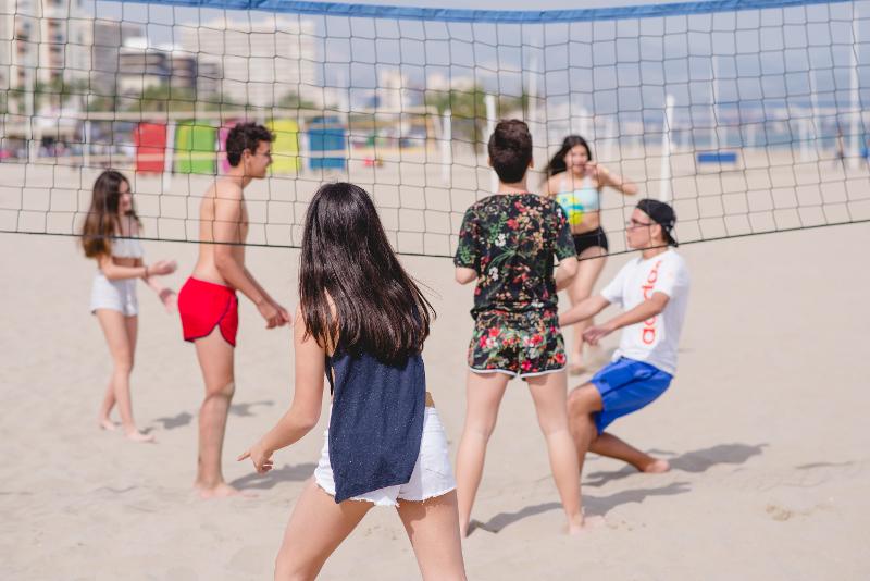 Beim Ferienlager am Meer spielen Kids Beachvolleyball