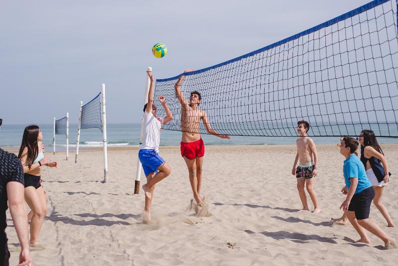 Teilnehmer eines Sprachcamps Kinder spielen am Strand Volleyball