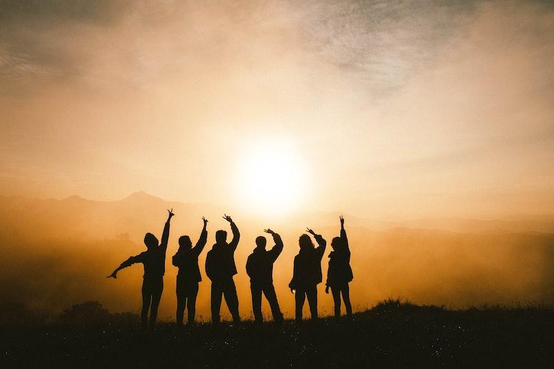 Teilnehmer eines Schülersprachkurses stehen in einer Reihe vor dem Sonnenuntergang und es sind nur Silhouetten zu sehen