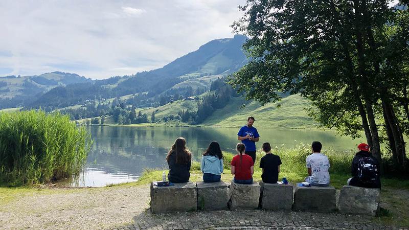 Enfants assis sur des pierres face à un lac