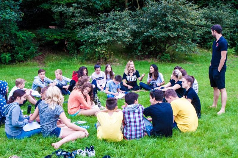 Eine Gruppe Jugendlicher sitzt gemeinsam auf einer Wiese