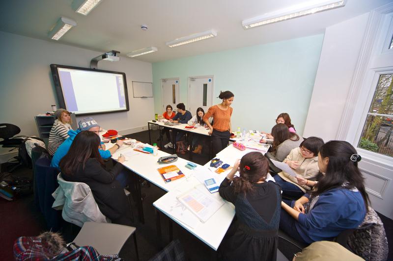 Teilnehmer einer Sprachreise für Schüler sitzen an Tischen in einem Klassenraum und lernen Englisch