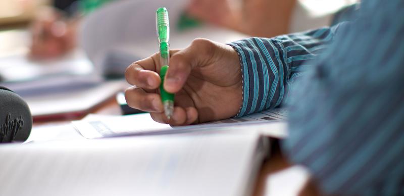 Eine Hand hält einen Stift und schreibt auf ein Blatt Papier beim Fremdsprachenkurs im Skilager.