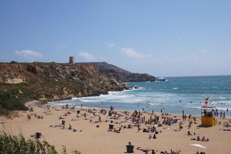 Blick auf den Strand mit Badegästen und Wellen auf Malta